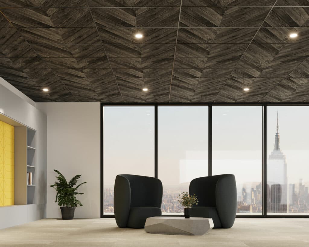 A modern office with a view, featuring two black chairs and a geometric coffee table. The ceiling boasts dark herringbone-patterned printed acoustic felt panels, while large windows display a skyline with a prominent skyscraper. A small potted plant sits near a wall with built-in shelves.