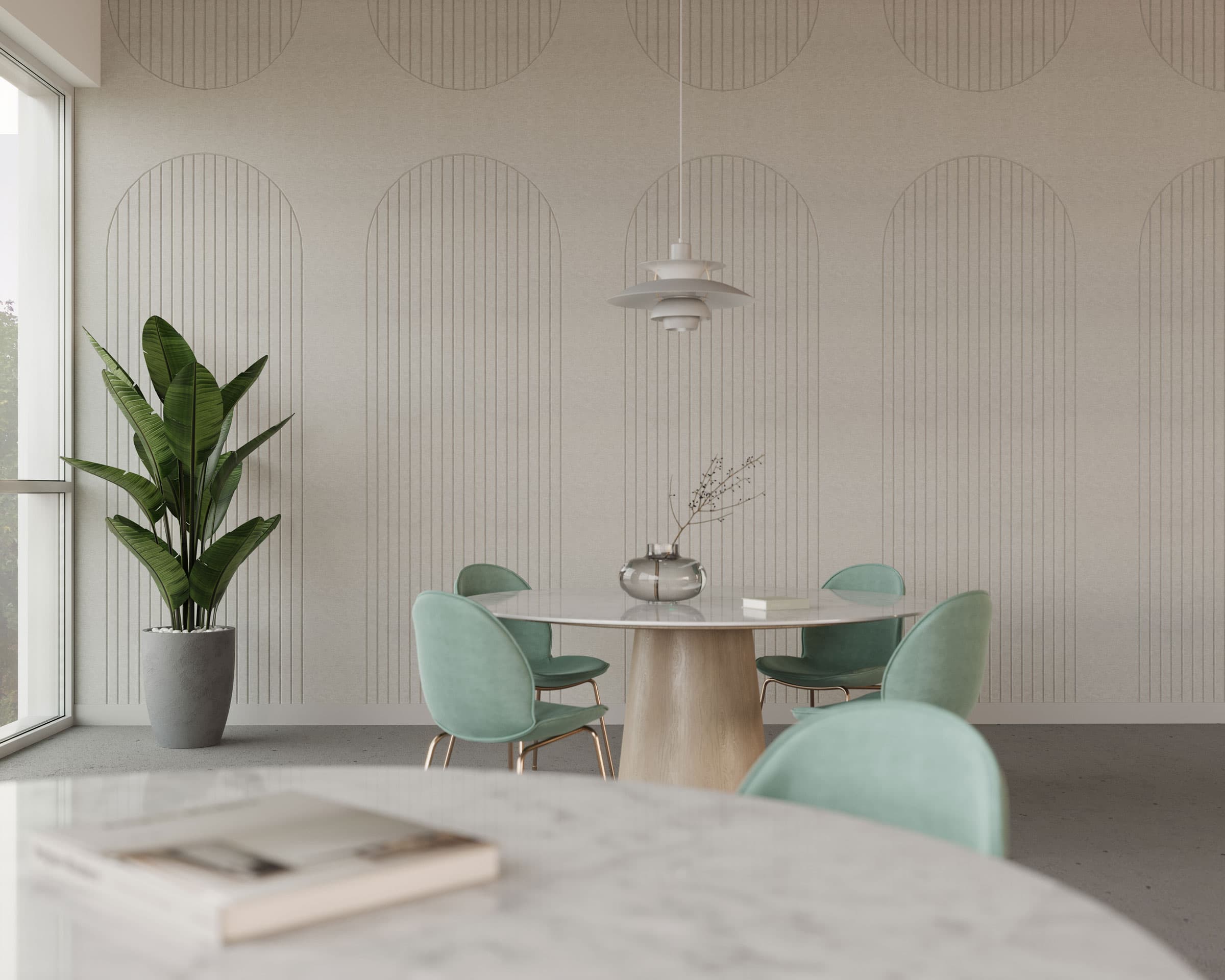 A minimalist dining area features a round table with a light wood base and a white marble top. Four pastel green chairs encircle the table, which holds a small, clear vase with delicate branches. Arch acoustic felt wall panels add subtle texture and enhance the room's acoustics beside the large plant in a grey pot by the windows.