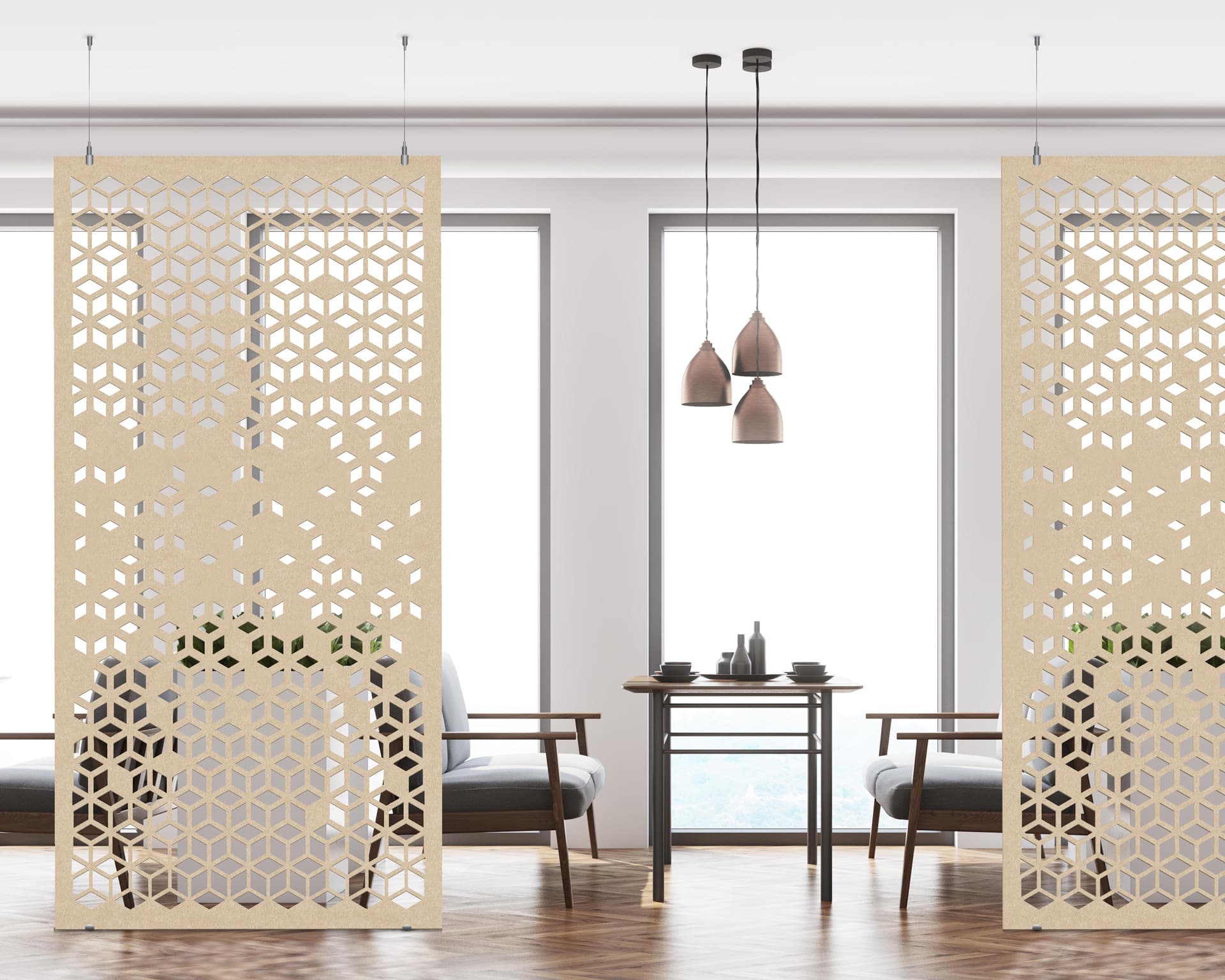 A modern room with large windows features two decorative acoustic felt screens with hexagonal cutout patterns. Between the screens are two gray armchairs facing a small table. Above the table hang three pendant lamps with brown shades.