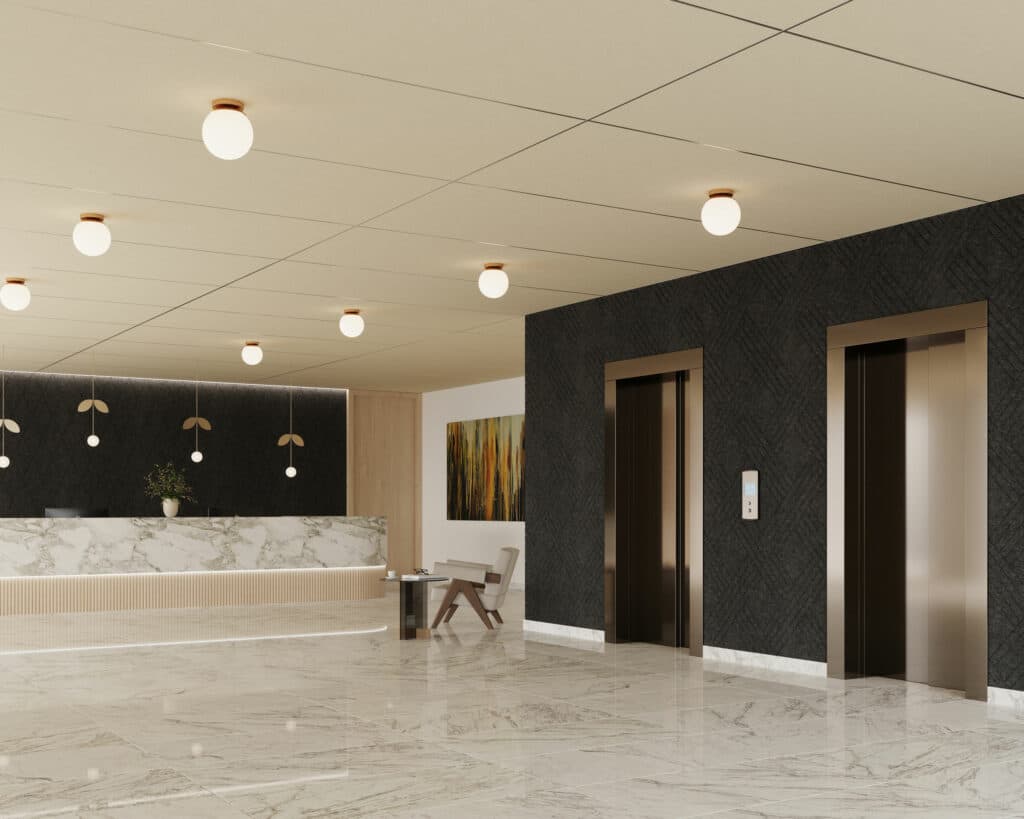 A modern hotel lobby with marble flooring features two elevators with dark textured walls on the right. The reception desk, adorned with a marble front and three pendant lights above, sits on the left. Solid acoustic felt ceiling panels enhance the ambiance, while a modern chair and small table occupy the corner.