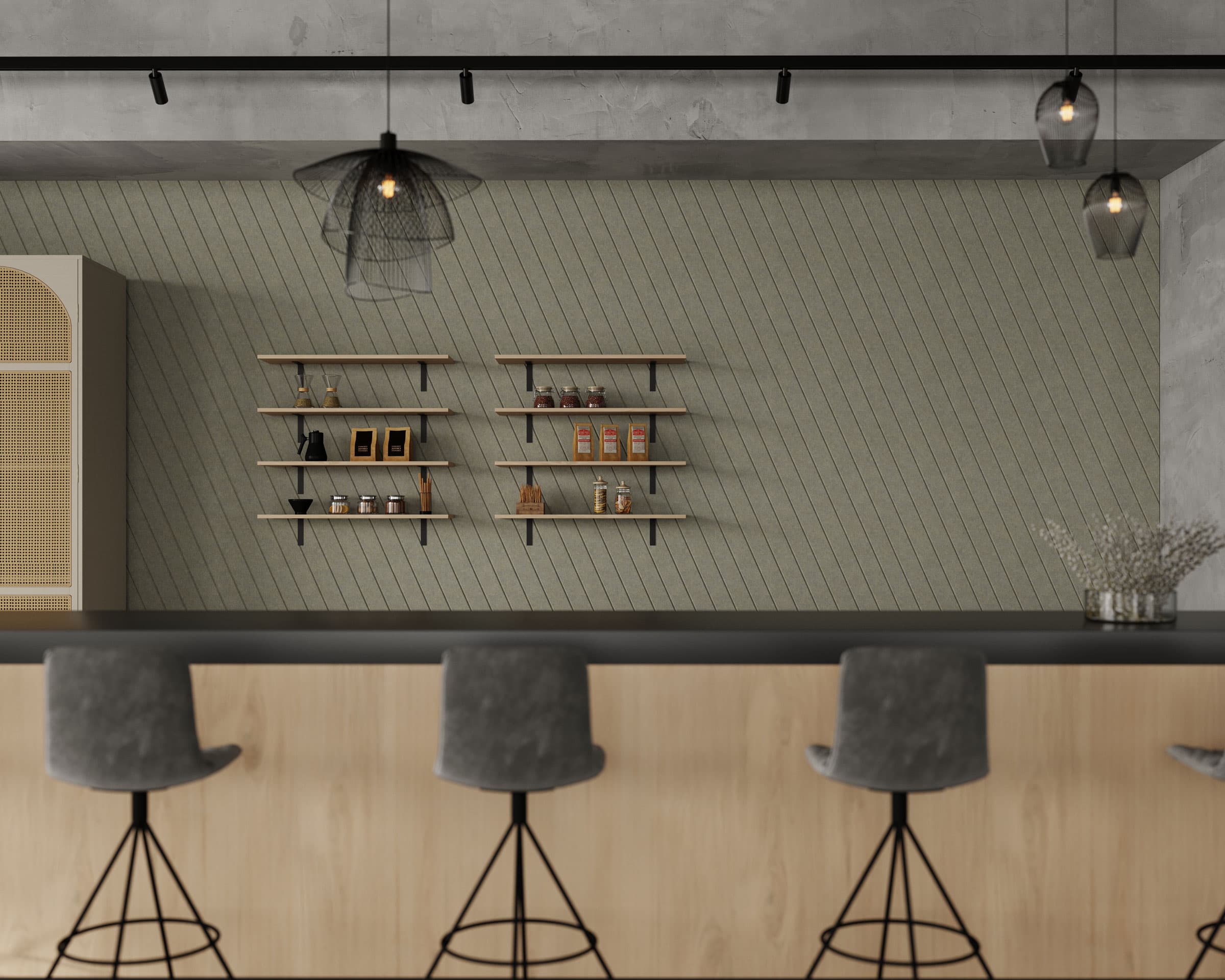 A modern kitchen with a sleek black countertop and four gray cushioned bar stools with metal legs. The light gray diagonal acoustic felt wall, features several wooden shelves displaying jars, spices, and small decorative items. Black pendant lights hang from the ceiling.