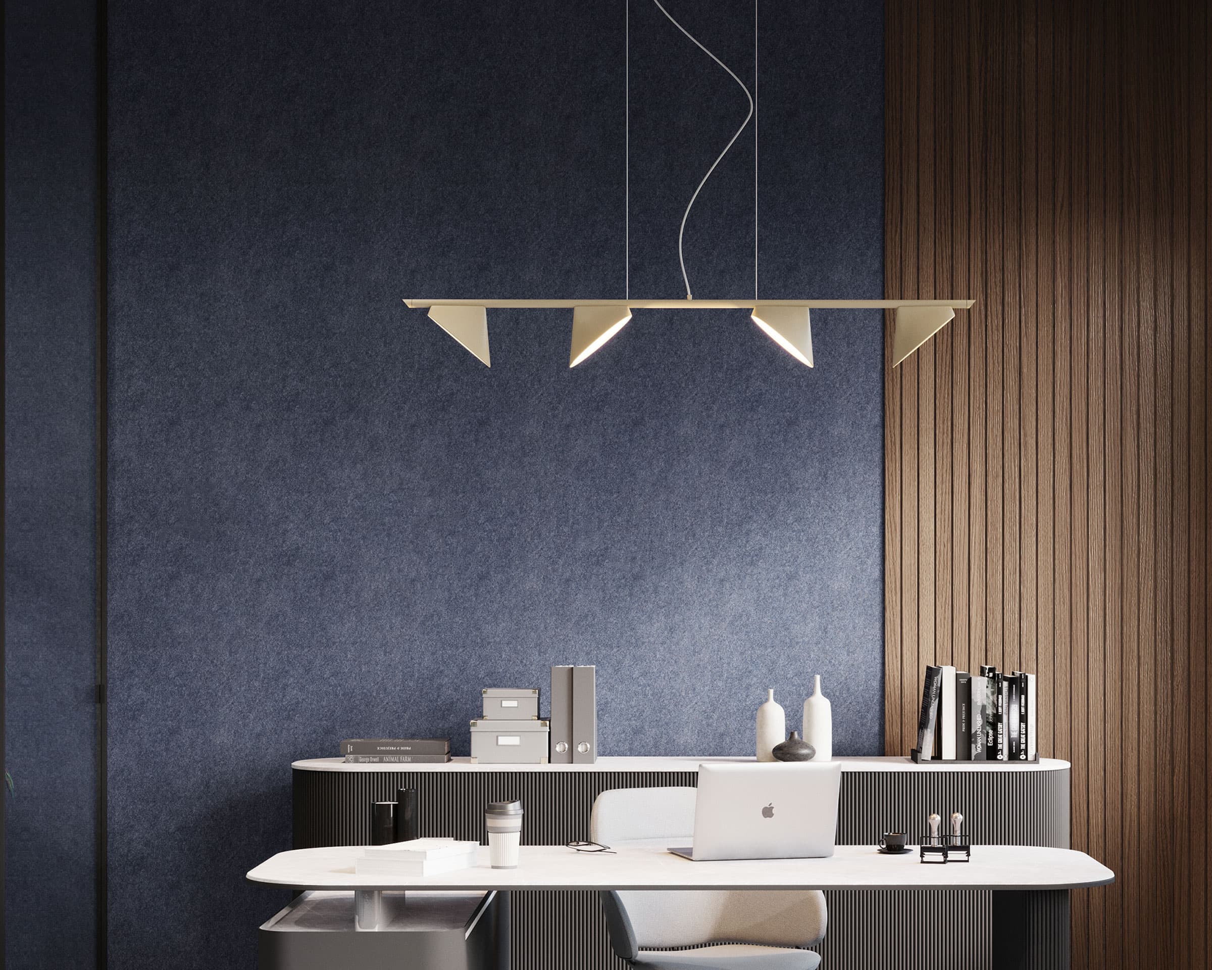 A modern office features a minimalist white desk with a laptop, books, and office supplies on it. Behind the desk is a wall adorned with a dark blue acoustic felt wall panel. Above the desk hangs a stylish, geometric pendant light fixture.