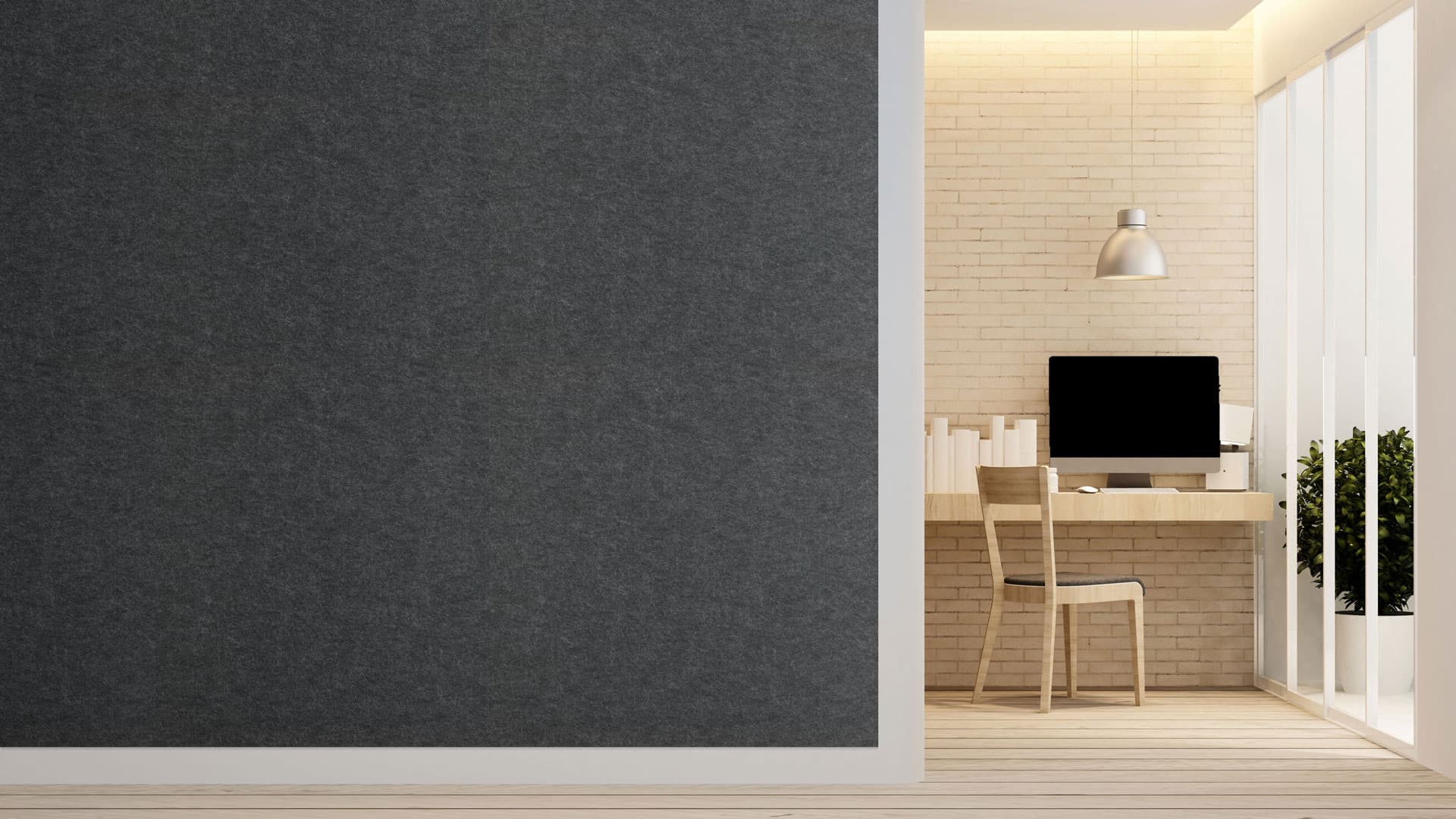 A modern minimalist office space featuring a tidy wooden desk with a computer monitor, a sleek chair, and a cluster of neatly arranged books. The room is softly lit by a pendant light, and an acoustic felt wall panel enhances tranquility while a potted plant adds greenery by the tall window.