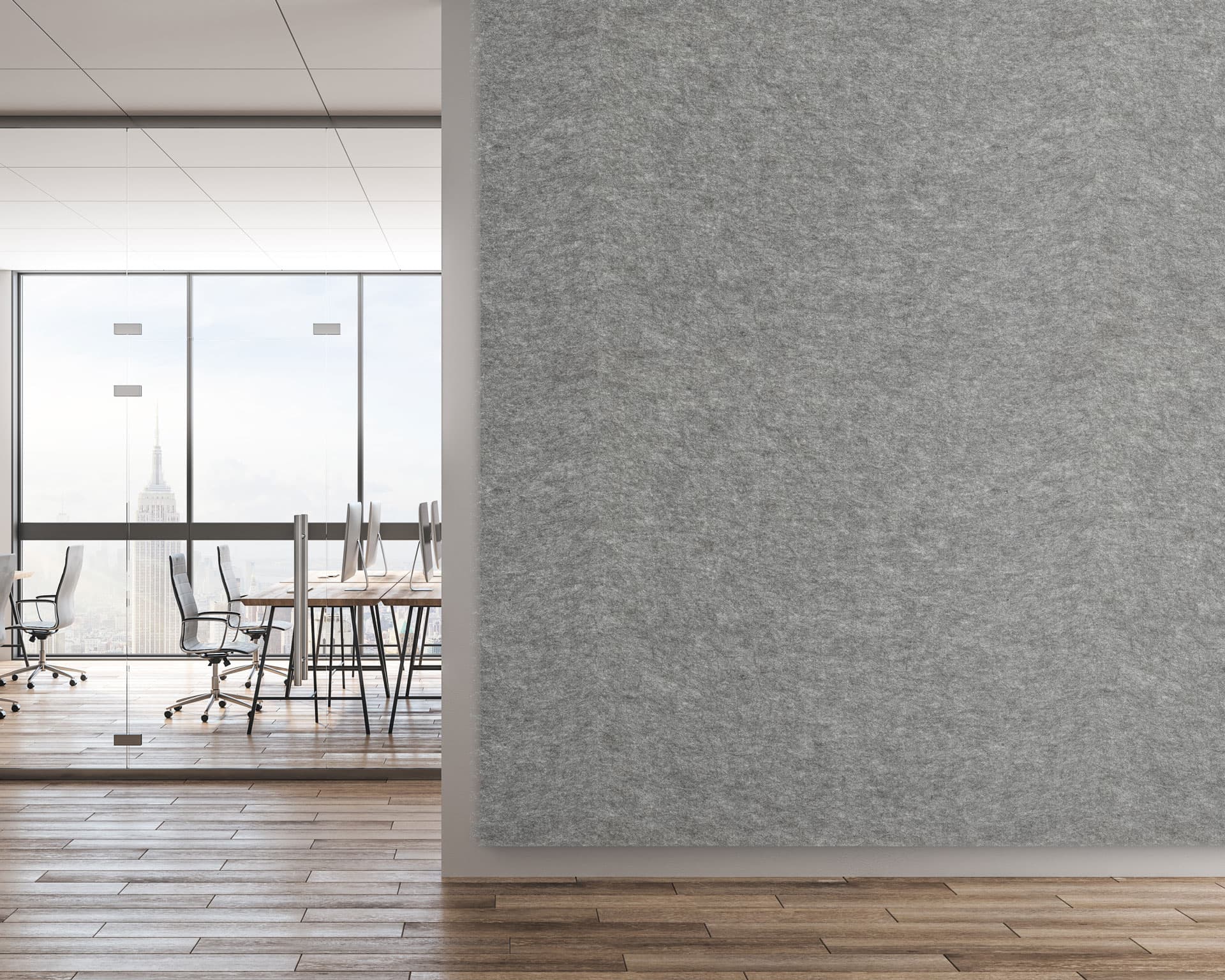 A modern office space with floor-to-ceiling glass windows showcasing a cityscape. The room features wooden flooring, glass-walled meeting spaces with white tables and black office chairs. In the foreground, a large acoustic felt wall panel enhances both aesthetics and sound quality.