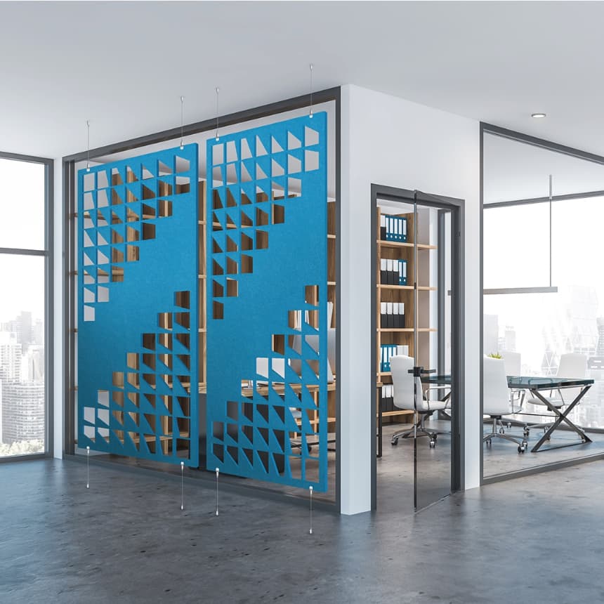 A modern office space with glass walls, featuring a uniquely designed blue acoustic felt screen with a geometric triangular pattern, ensuring privacy. Inside the office, there's a desk, a chair, shelves, and large windows providing a view of a cityscape with tall buildings.