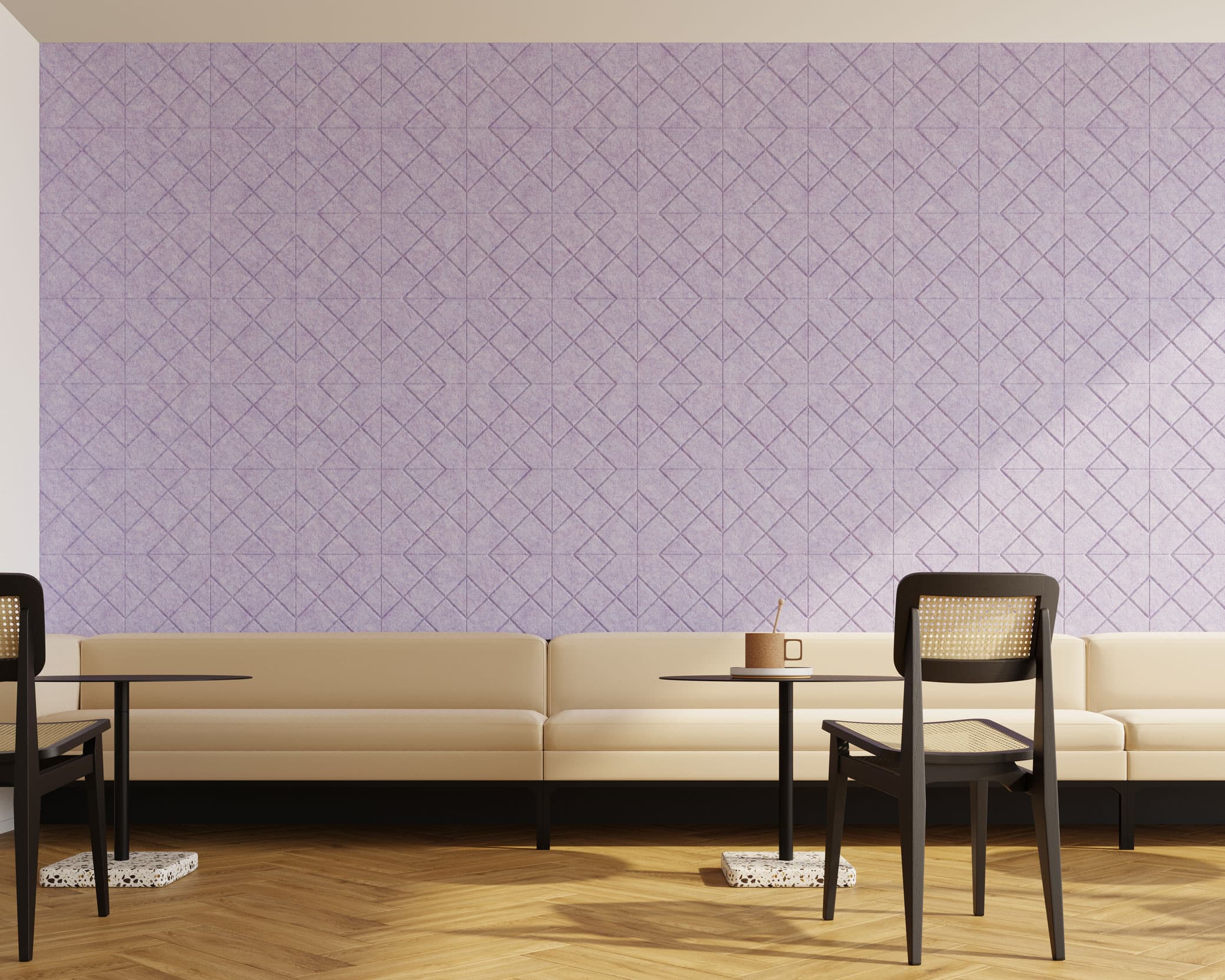 Minimalistic café interior with cream-colored bench seating along a wall covered in geometric, light purple acoustic felt wall tiles. Two small, black tables with single chairs are positioned on light wooden flooring, and natural light casts soft shadows into the room.