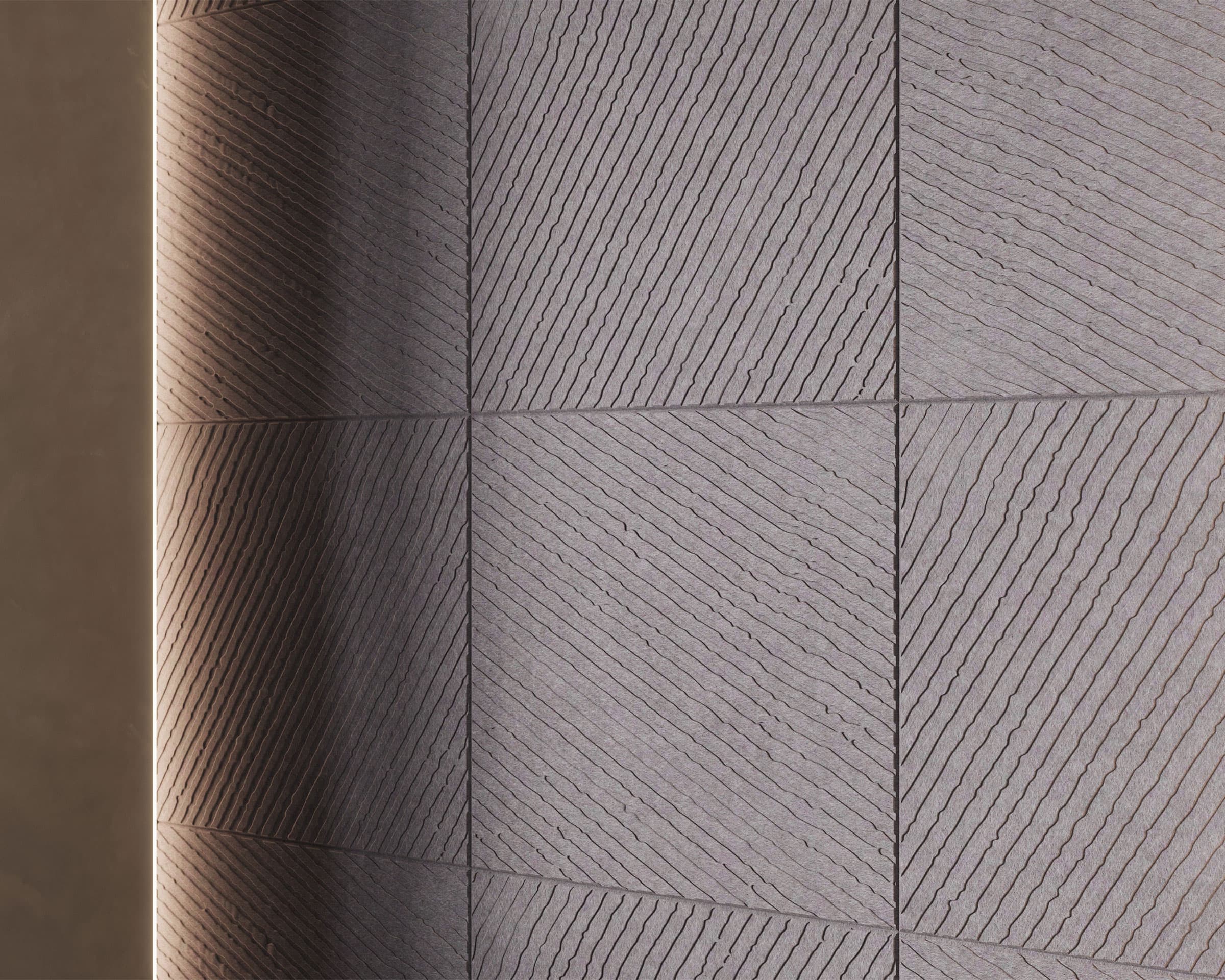 A close-up image of a textured wall featuring large square acoustic felt wall tiles arranged in a grid. Each tile has a diagonal striped pattern with alternating ridges and grooves. The wall is illuminated from the left side, highlighting the texture.