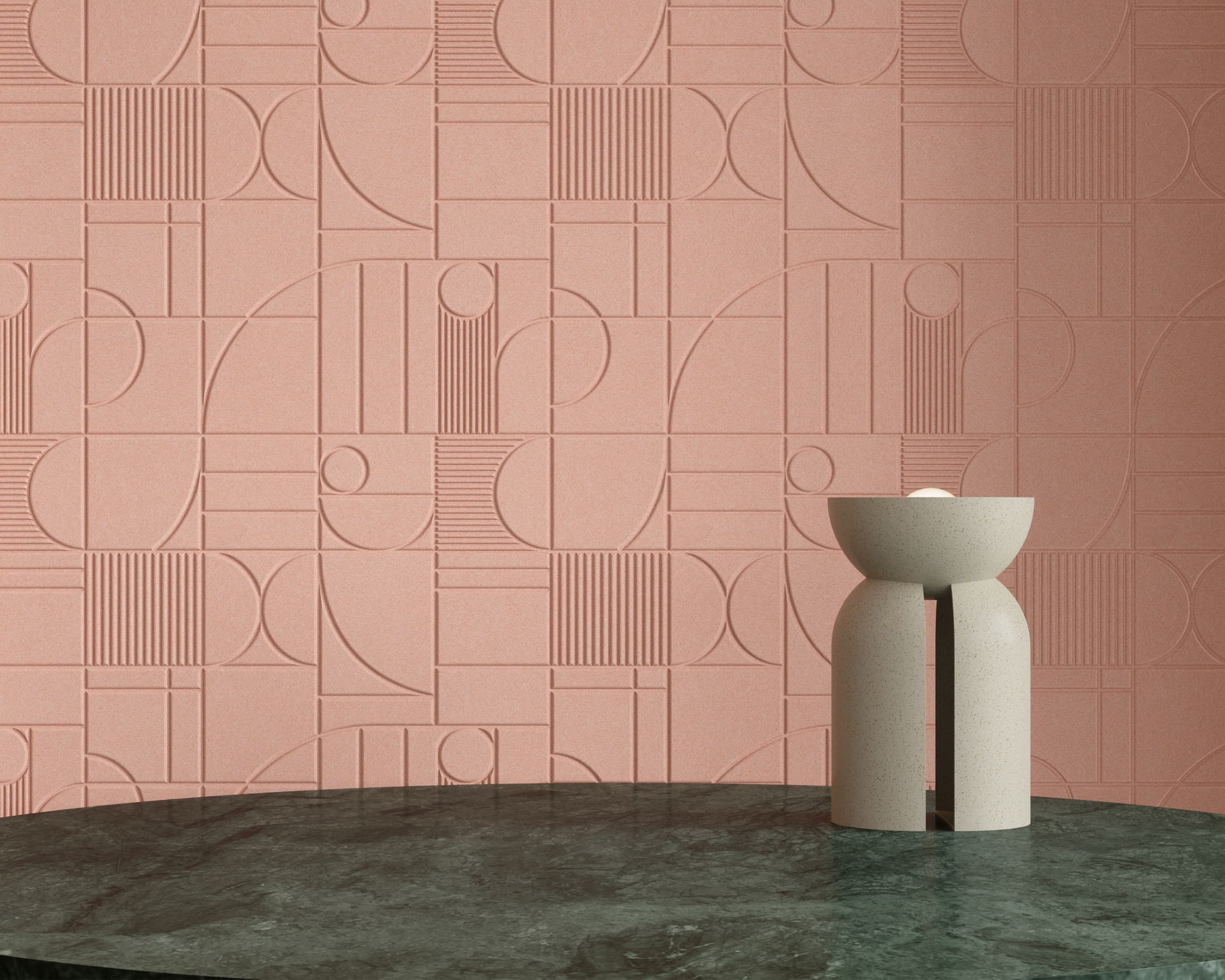 A textured acoustic felt wall with an abstract geometric pattern in a muted pink shade, featuring overlapping circles, lines, and rectangles. In the foreground, a dark green marble table holds a minimalistic cream-colored vase with two connected cylindrical shapes, each holding a sphere.