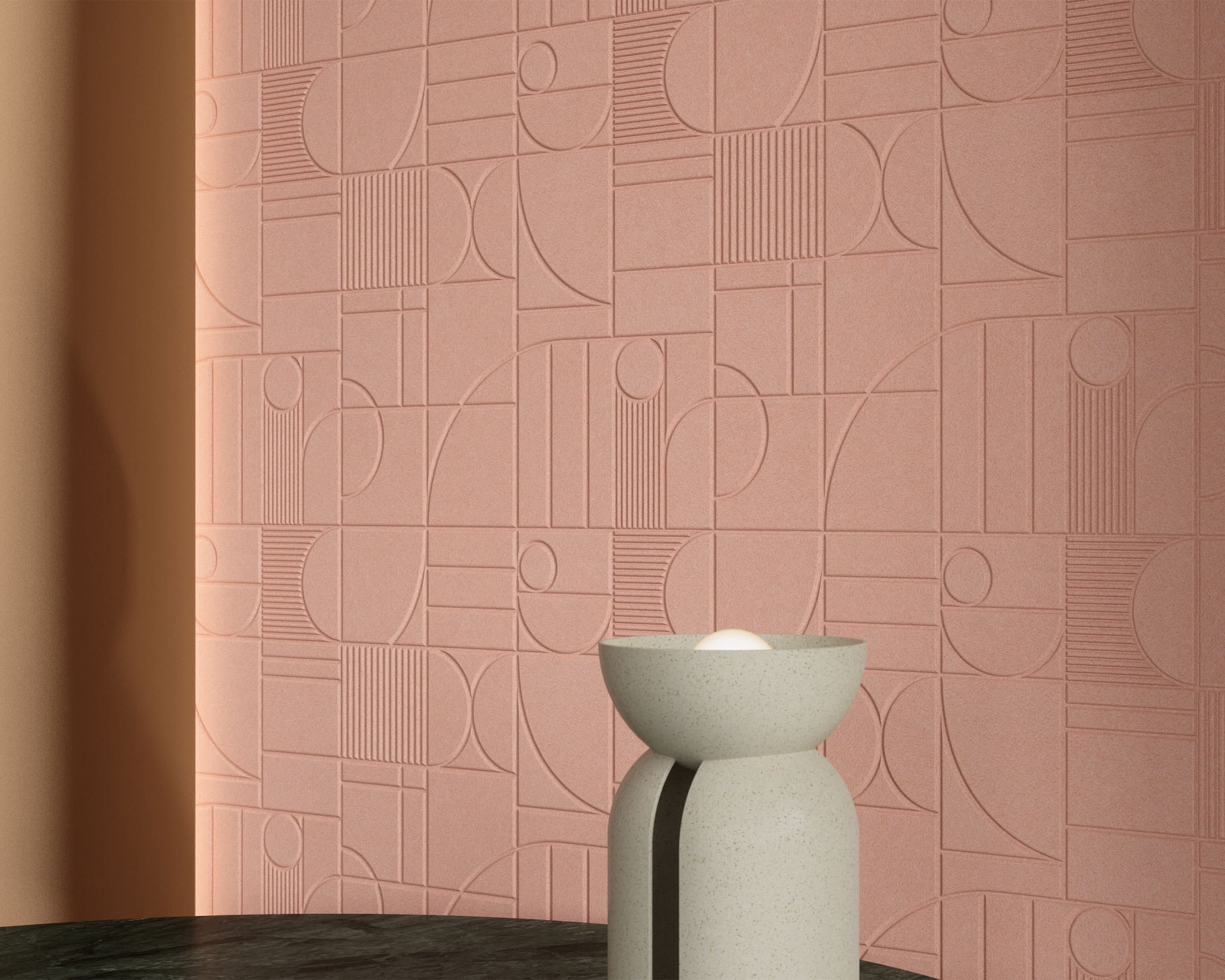 A minimalist scene featuring a textured wall with geometric patterns in shades of pink, created using acoustic felt wall tiles. In the foreground, a modern, beige stone planter with a small plant sits on a dark green, shiny surface. Soft lighting adds warmth to the setting.