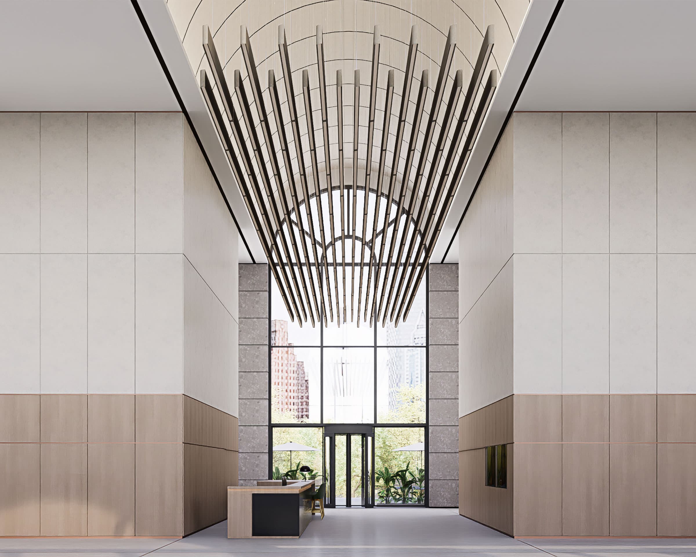 A modern, spacious lobby with high ceilings features a striking, symmetrical hanging light fixture made of vertical rods. The minimalistic design includes light-colored walls, wooden panels, and acoustic ceiling baffles. At the far end, large windows offer a view of buildings and trees outside.