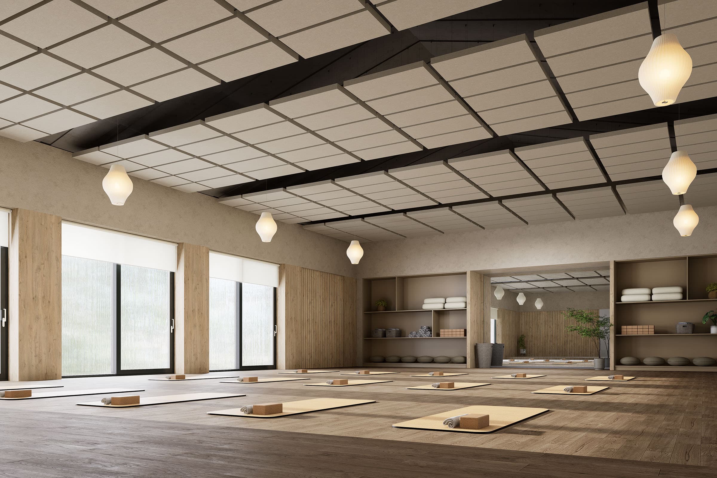 A serene yoga studio with mats, blocks, and rolled towels neatly arranged. The room has large windows allowing natural light to flood in, soft pendant lights hanging from the ceiling, and shelves stocked with additional yoga supplies and potted plants. Acoustic felt ceiling clouds add a touch of tranquility.