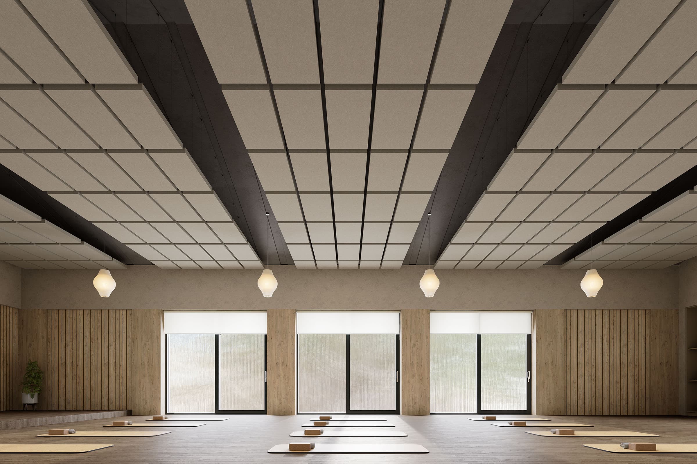 A spacious, modern yoga studio with wood-paneled walls and a grid-patterned ceiling. The floor is lined with yoga mats and wooden blocks, positioned evenly in rows. Large windows at the front provide natural light, while acoustic felt ceiling clouds and hanging lanterns add ambient lighting.