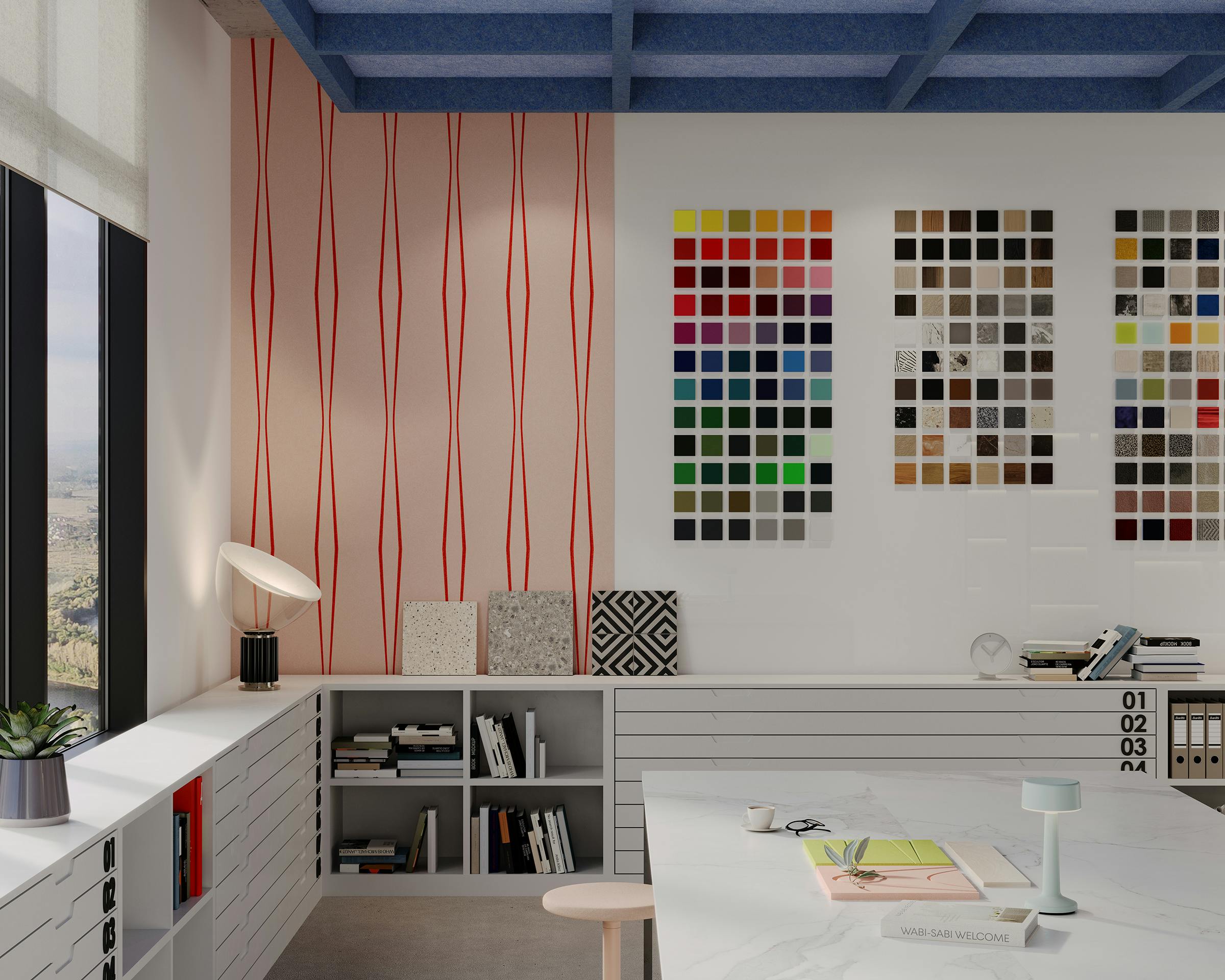 A modern design studio featuring a large table with various materials and a colorful pen holder. The background wall displays vibrant color swatches, and a side wall has abstract wave patterns. A window lets in natural light, illuminating the capped framework ceiling and meticulously arranged decor.
