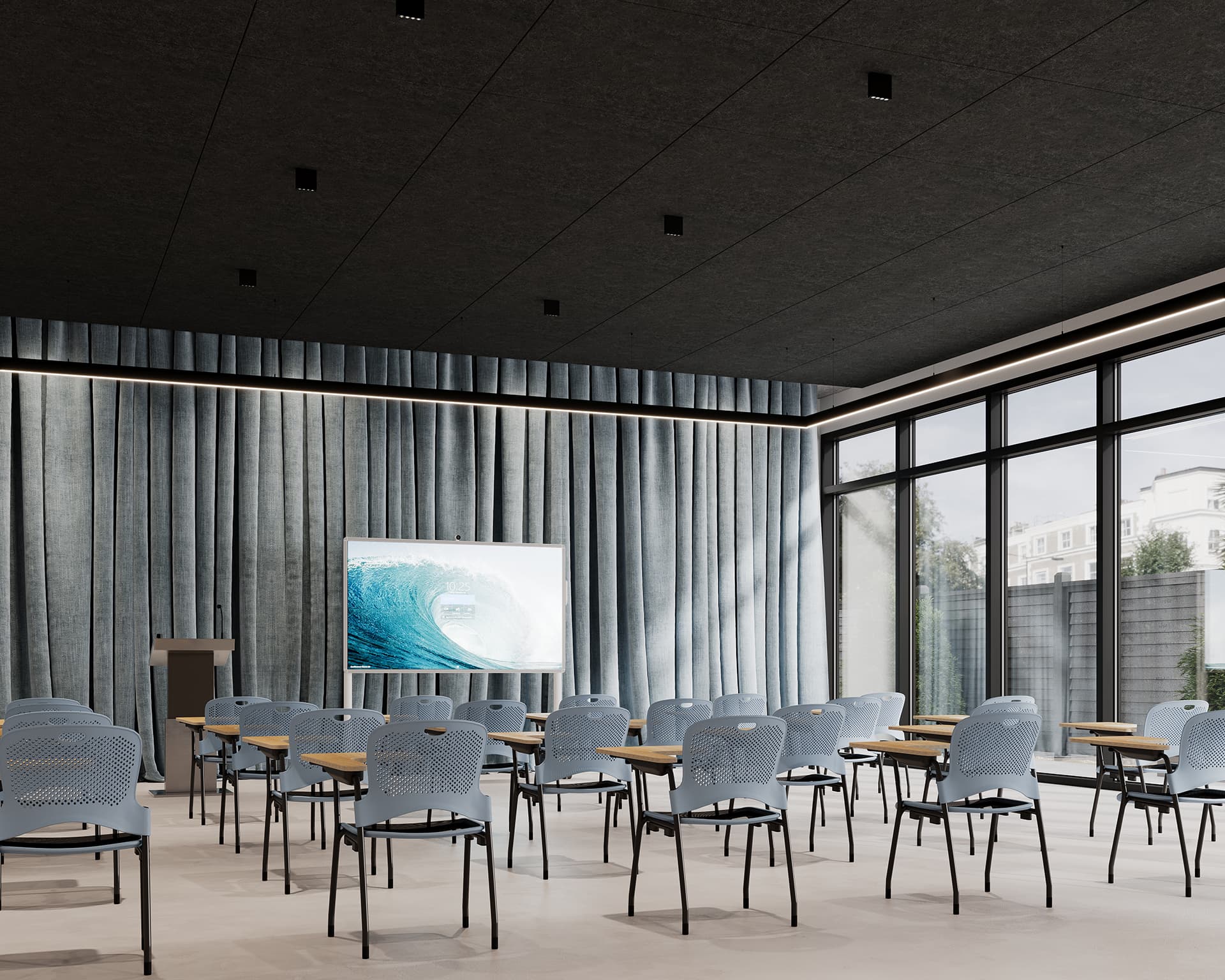 A modern conference room with rows of blue chairs and attached desks facing a podium and a large screen displaying an image of a wave. Floor-to-ceiling windows line the right side, letting in natural light, while gray curtains cover the back wall.