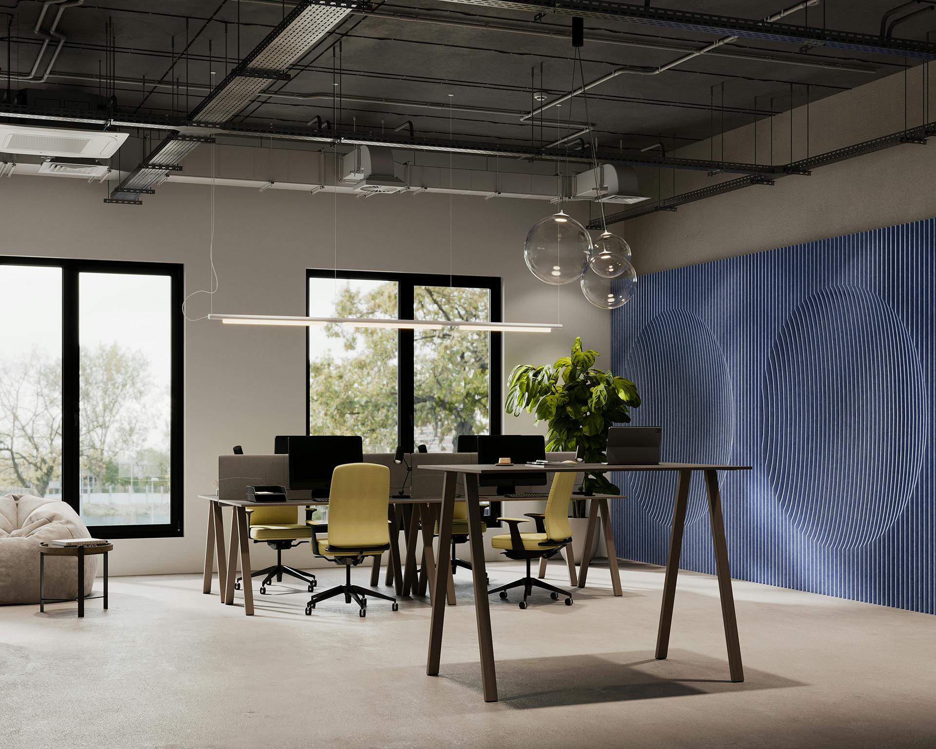 A modern office space featuring multiple desks with computers and green chairs. A tall table with a laptop is positioned in the foreground, and a leafy green plant adds a touch of nature. Large windows and a blue textured wall enhance the room's contemporary feel.