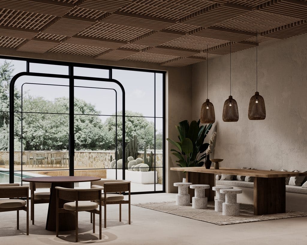 A modern dining room features a wooden table with stools, three wicker pendant lights, and a second wooden table with chairs. The room has large glass doors opening to an outdoor area with trees and cacti, and a unique acoustic felt ceiling design with geometric wooden patterns.