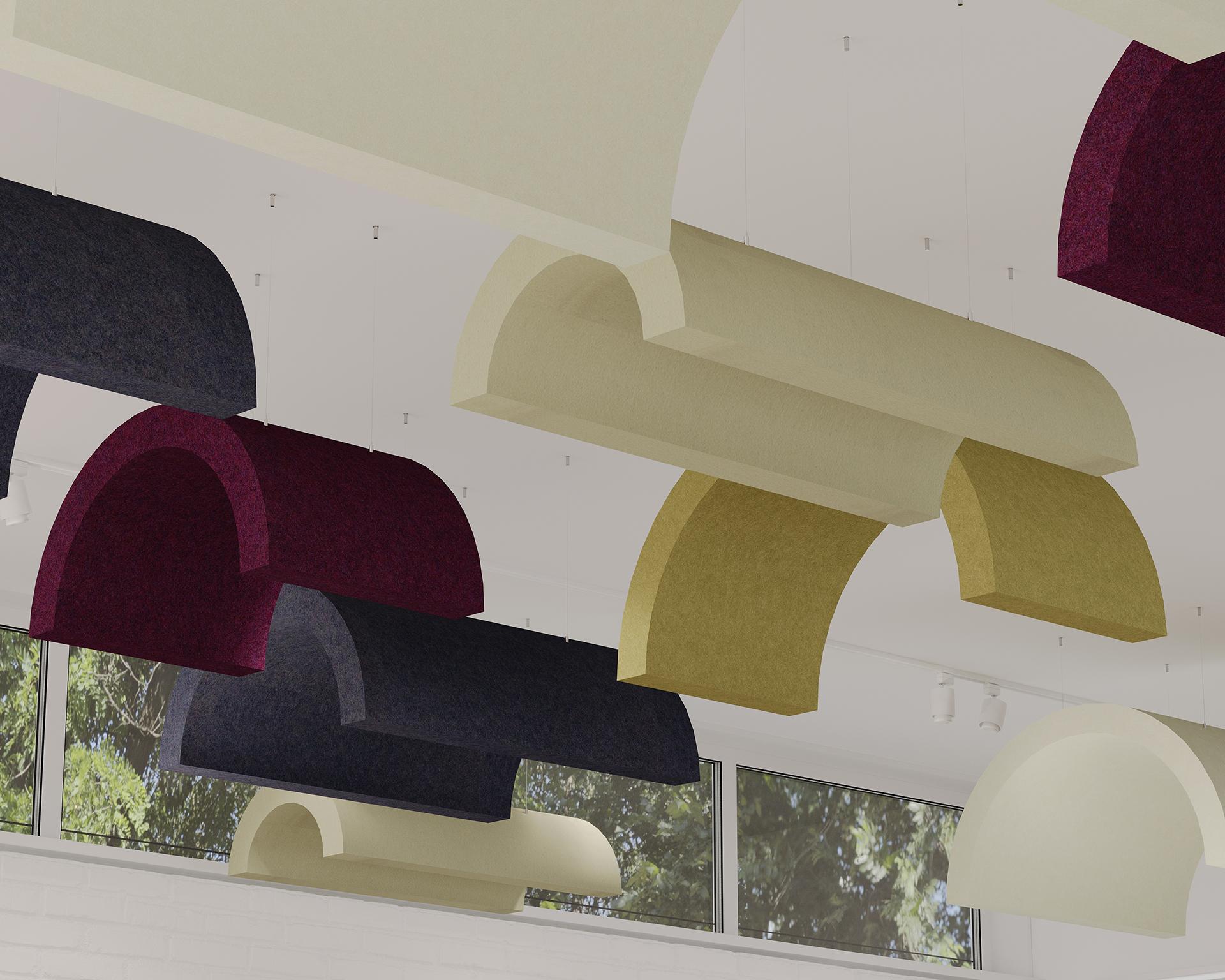 Curved acoustic felt ceiling clouds in shades of beige, maroon, dark navy, and green are suspended from a white ceiling. Large windows below the panels allow in natural light, with trees visible outside. The panels create a modern, geometric ceiling design.