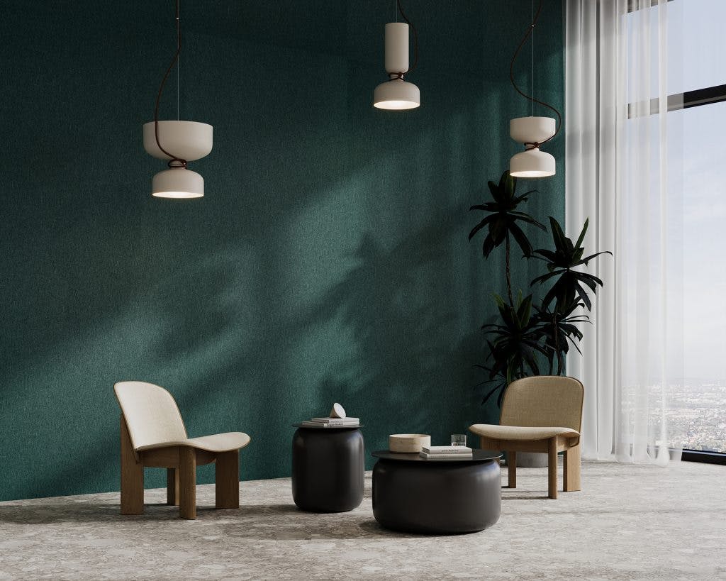 A minimalist room with a dark green acoustic felt accent wall features two light wood and beige fabric chairs, two round black coffee tables, and three pendant lights. A large window with sheer white curtains lets in natural light, revealing a view of the cityscape outside.