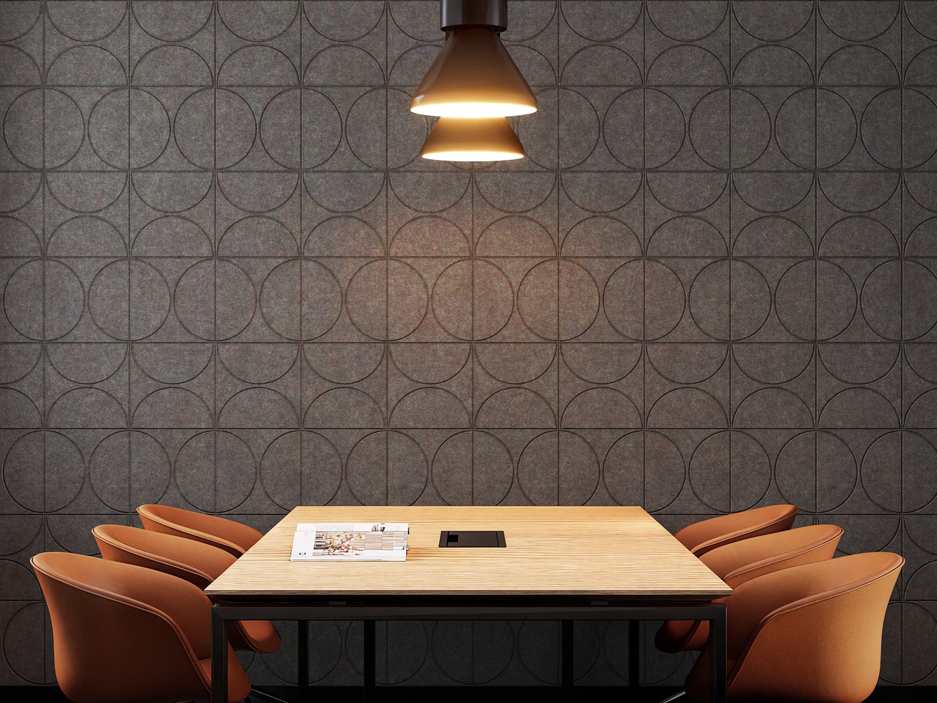 A modern meeting room features a square wooden table with four brown chairs. A black pendant light hangs above, casting a warm glow. The wall is adorned with a geometric acoustic felt circle pattern, and a small stack of papers rests on the table.